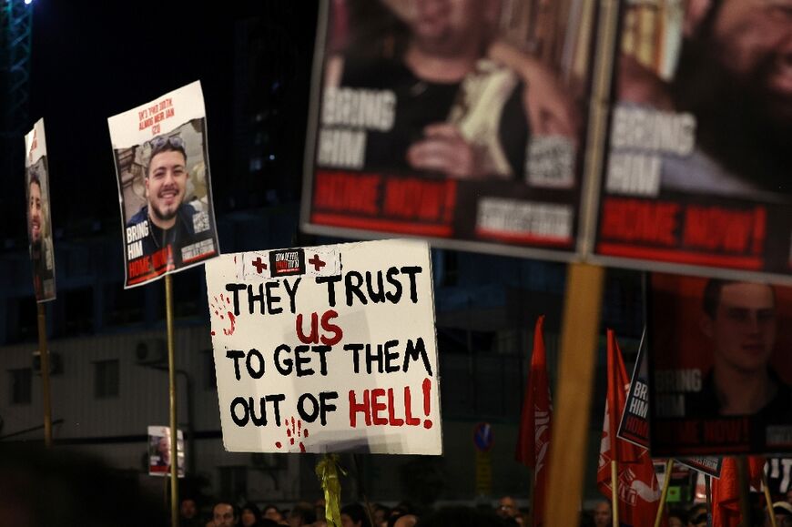 Relatives and supporters hold placards, some bearing portraits of Israeli hostages held in Gaza, during a rally calling for their release, in Tel Aviv on January 6, 2024