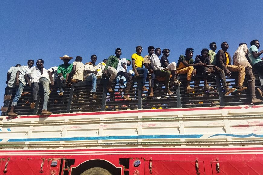 People displaced by the conflict inSudanride atop the back of a truck moving along a road in Wad Madani, the capital of al-Jazirah state