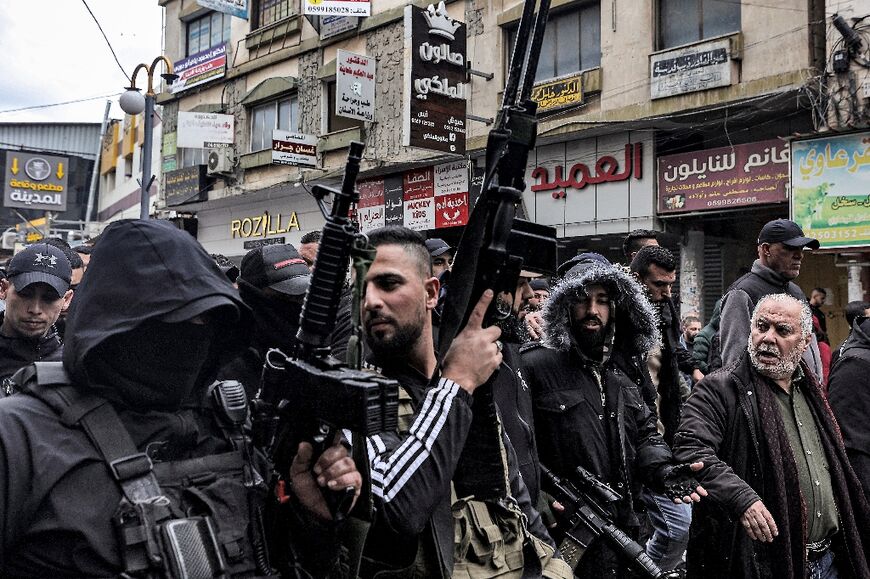 Armed militants join the funeral procession for two of the three Palestinians killed by Israeli undercover agents in a hospital in the West Bank city of Jenin