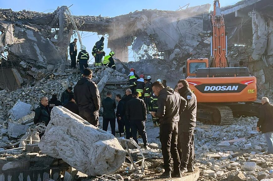 Iraqi firefighters inspect the rubble of a building in Arbil hit by an Iranian missile strike