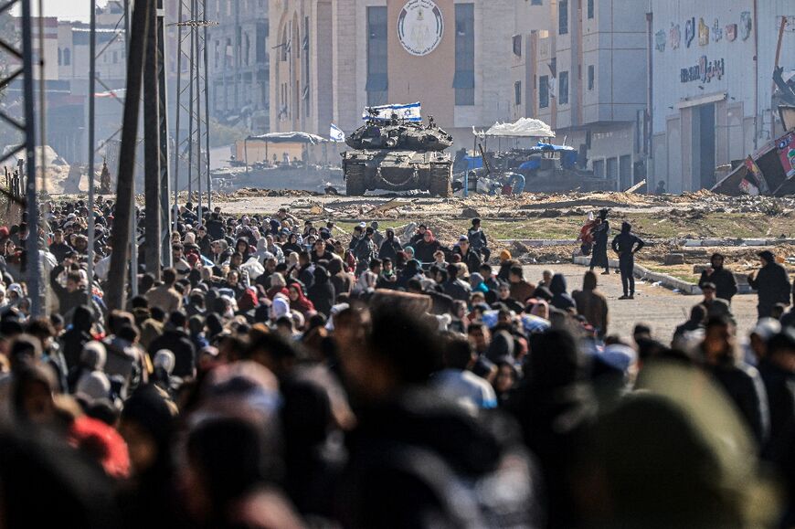 An Israeli tank and other military vehicles guard a position as Palestinians flee Khan Yunis