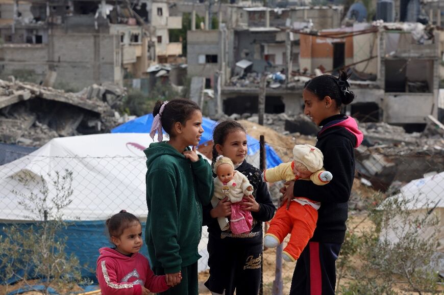 Palestinian children play in front of rubble at a makeshift camp housing displaced Palestinians in Rafah in the southern Gaza Strip on January 28, 2024