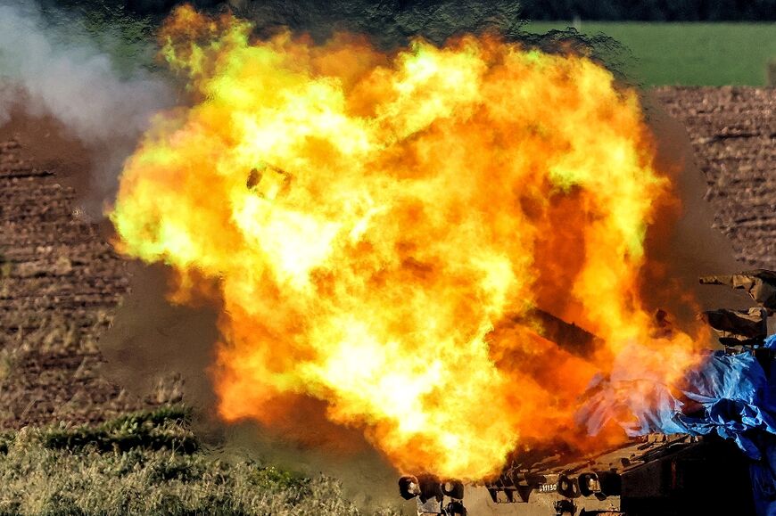 A burst of flame erupts from an Israeli army self-propelled Howitzer, firing from southern Israel toward the Gaza Strip