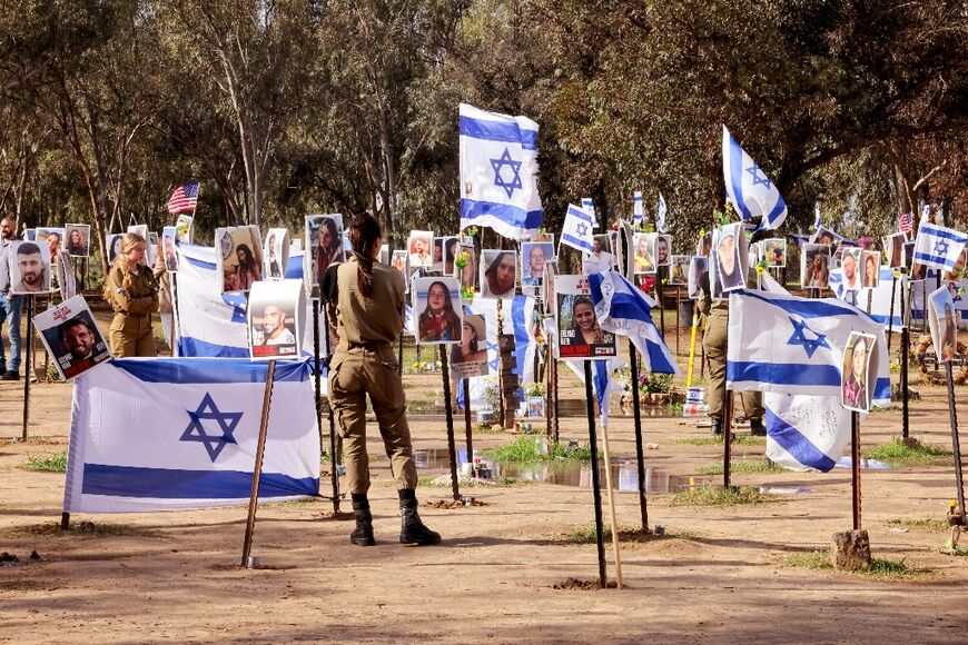 Israeli soldiers walk among portraits of people taken captive or killed by Hamas militants during the Supernova music festival on October 7