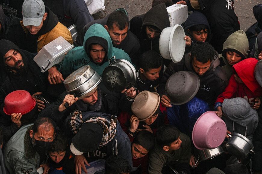 Palestinians receive food rations at a donation point at a camp for displaced people in Rafah