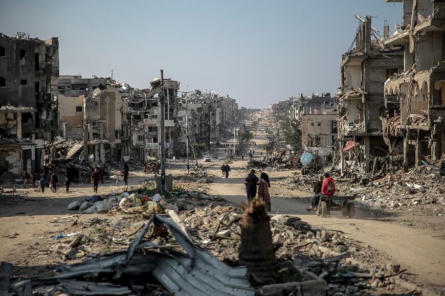 Palestinians walk past bombed out buildings in Beit Lahia in northern Gaza