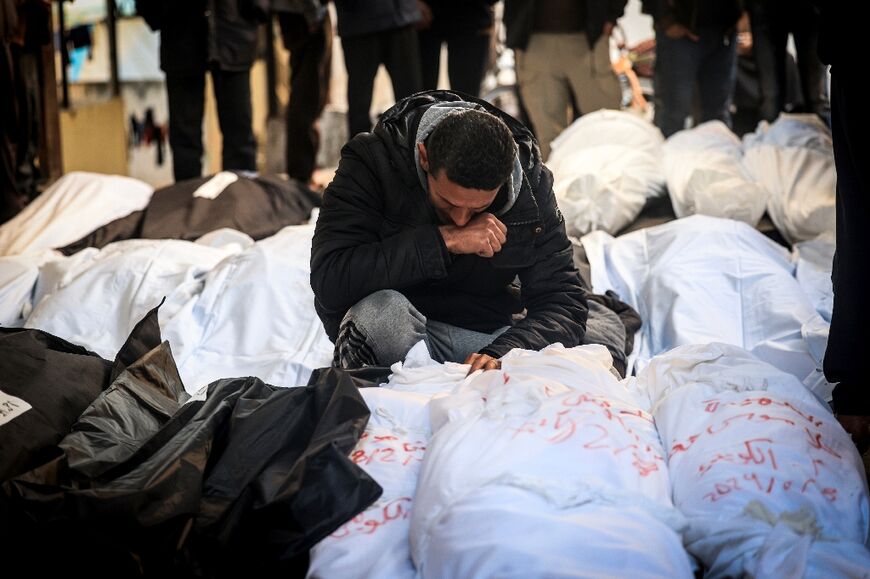 A Palestinian man mourns over shrouded bodies of relatives killed in overnight Israeli bombardment on the southern Gaza Strip at Al-Najjar hospital in Rafah on February 8, 2024