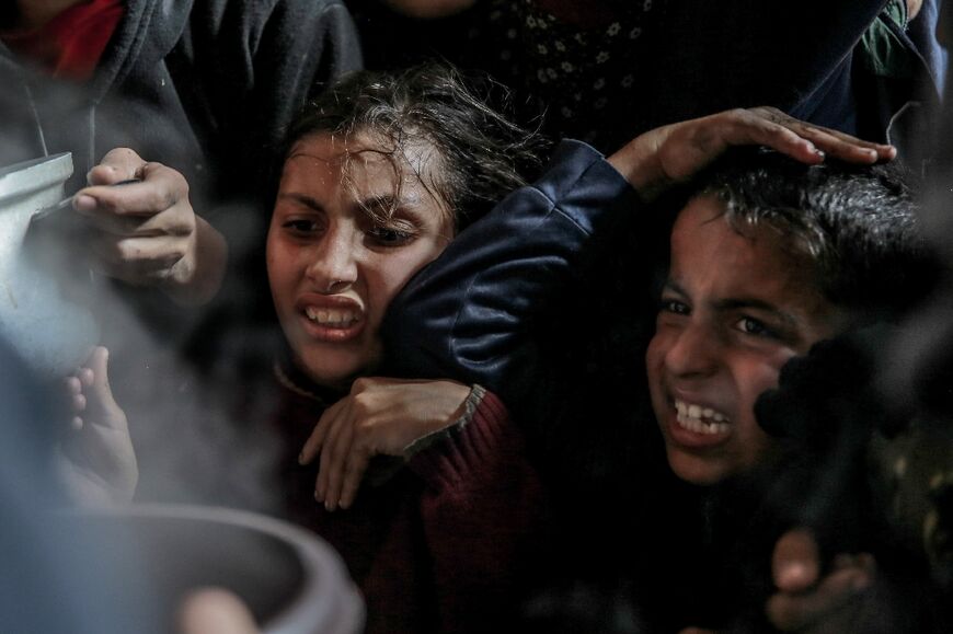 Palestinian children gather to collect food aid in Beit Lahia, the northern Gaza Strip