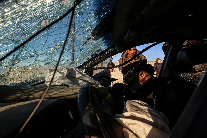 People check a damaged car in which three people were reportedly killed when it was hit by an Israeli strike in Rafah in the southern Gaza Strip on January 31, 2024