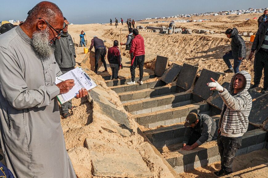 A man records the names of the dead during the funeral of Palestinians killed in overnight Israeli strikes at a cemetery in Rafah on February 21, 2024