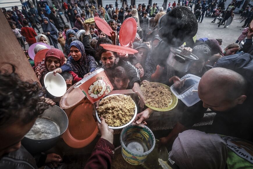 Aid agencies have warned of looming famine in Gaza, where displaced Palestinians in Rafah gathered to receive food at a government school