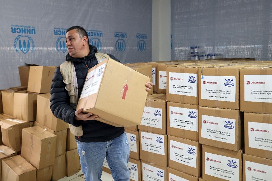 A volunteer carries a box of donations to be distributed to the displaced