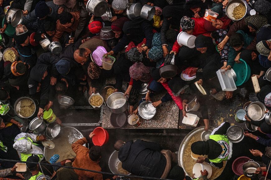 Palestinians receive food rations at a donation point at a camp for internally displaced people in Rafah 