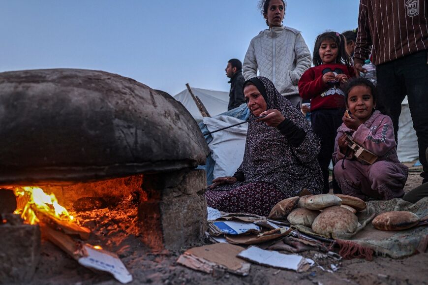 A displaced Palestinian woman bakes bread before an iftar meal, the breaking of fast