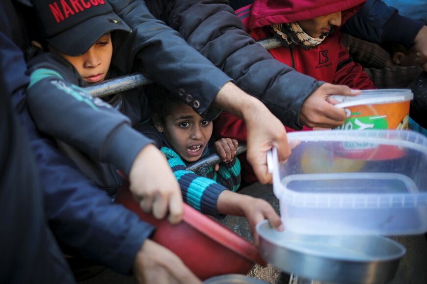 Displaced Palestinians are given food donated by a charity on the first evening of Ramadan in Rafah