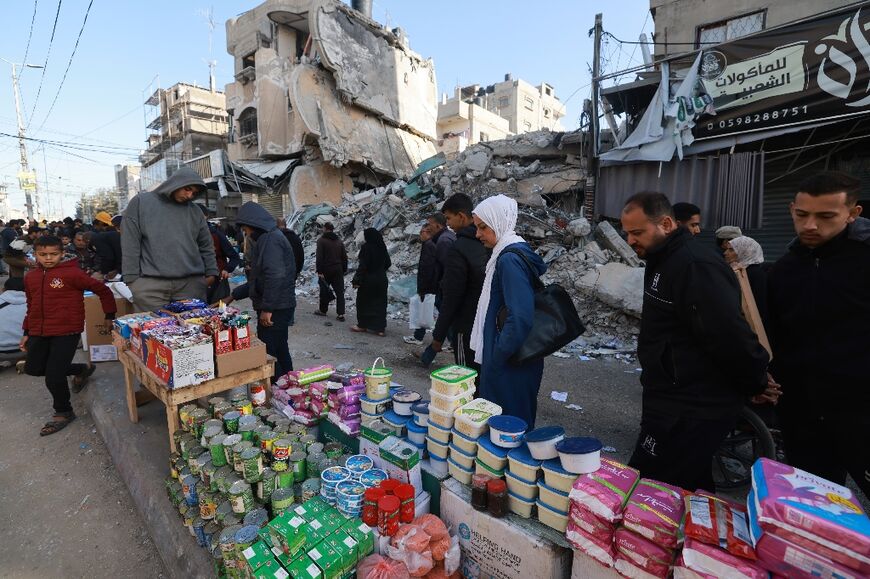 Palestinians walk past stalls in Rafah, the southern Gaza Strip ahead of the holy fasting month of Ramadan as famine threatens and prices have soared