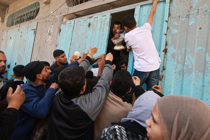 With famine threatening, Palestinians scramble to buy a small amount of sugar and sage from a shop at the Bureij refugee camp in the central Gaza Strip 