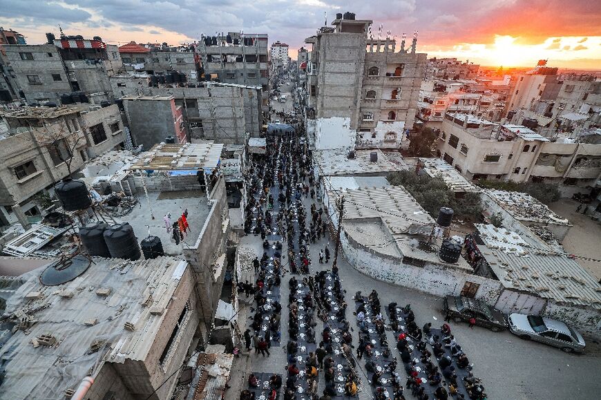 People sit together for a mass 'iftar' (fast-breaking) meal organised by members of the Barbara refugee camp during the Muslim holy month of Ramadan in Rafah 