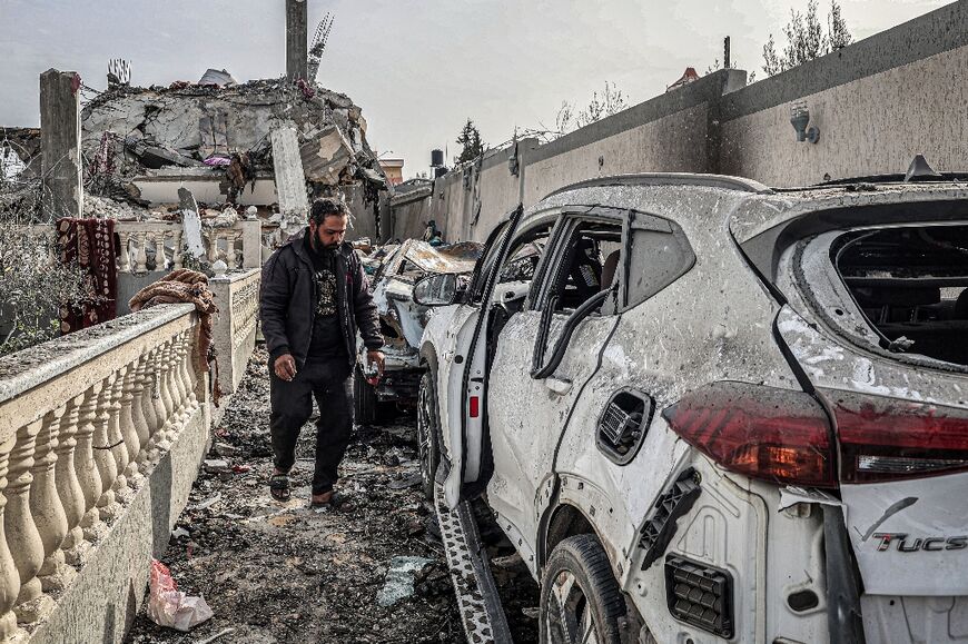 A man walks past destroyed cars outside a building that was hit overnight during Israeli bombardment in Rafah