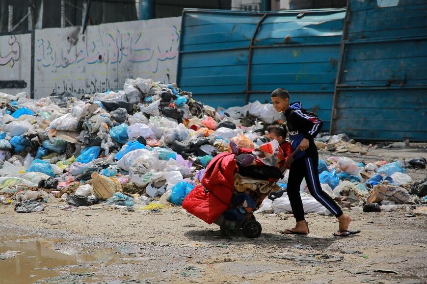 A child walks past a pile of household garbage in a street in Gaza City 