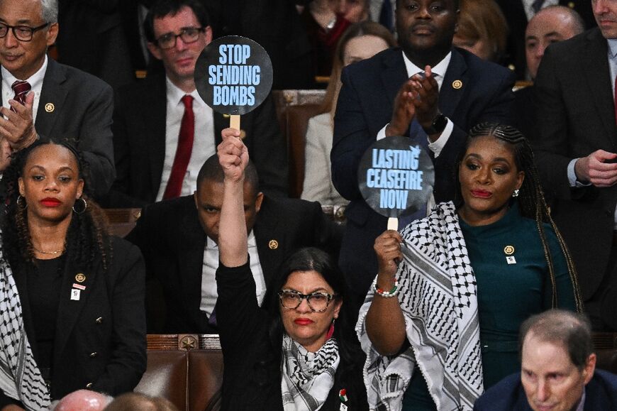 Representative Rashida Tlaib, Democrat of Michigan, and Representative Cori Bush, Democrat of Missouri, hold signs reading "Stop Sending Bombs" and "Lasting Ceasfire Now" as President Joe Biden delivers the State of the Union address 