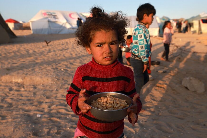 A Palestinian girl holds a bowl of beans before an iftar meal at a camp for displaced people in Rafah in the southern Gaza Strip