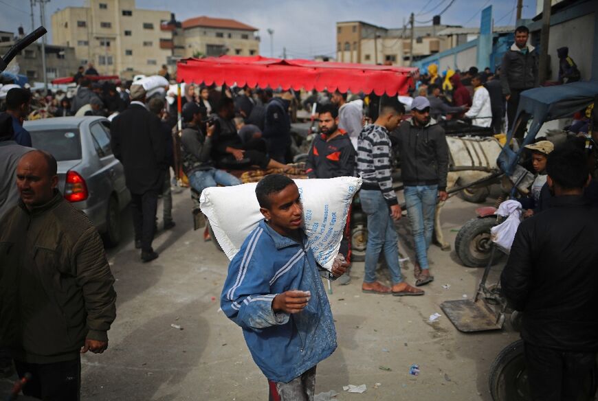 A Palestinian man carries a sack of humanitarian aid at the distribution center of the United Nations Relief and Works Agency for Palestine Refugees (UNRWA) in Rafah in the southern Gaza Strip on March 3, 2024