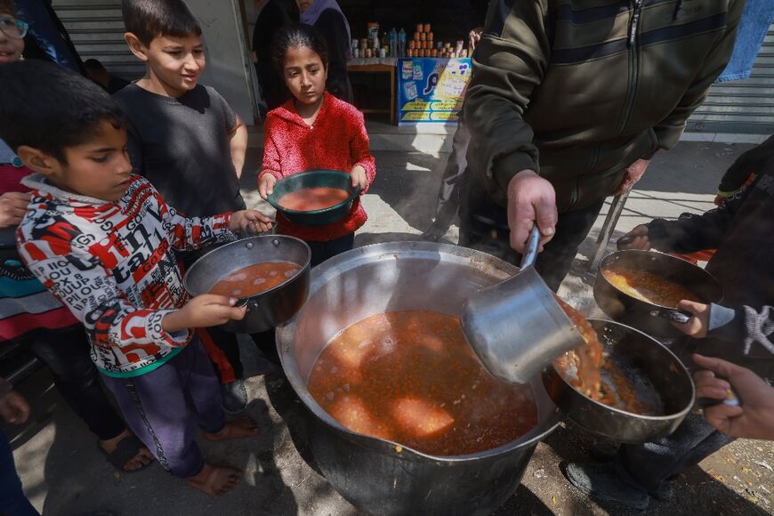 Palestinian children receive soup rations in Rafah in the southern Gaza Strip on March 5, 2024, amid widespread hunger in the besieged Palestinian territory 