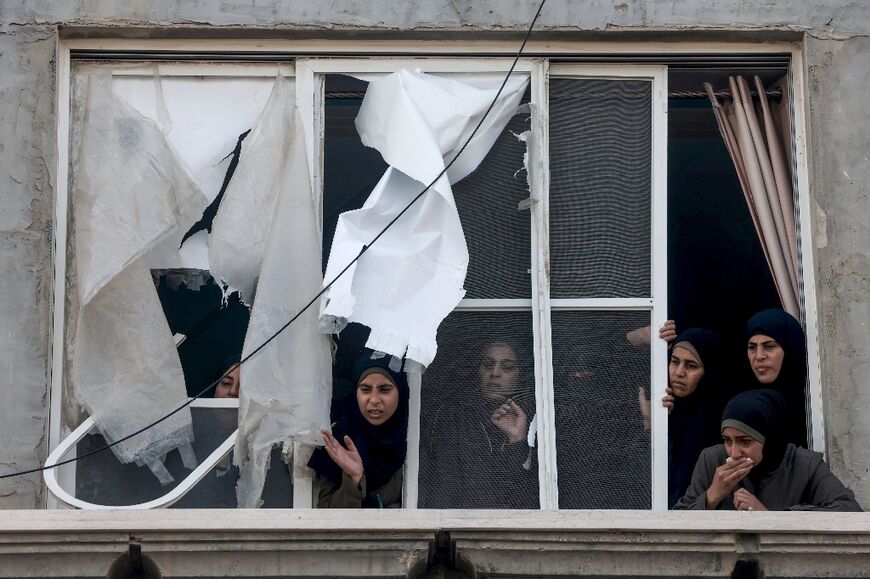 Palestinian women watch from a damaged apartment as dead relatives are transferred into a vehicle following overnight bombardment in Rafah in the southern Gaza Strip, on April 2, 2024 