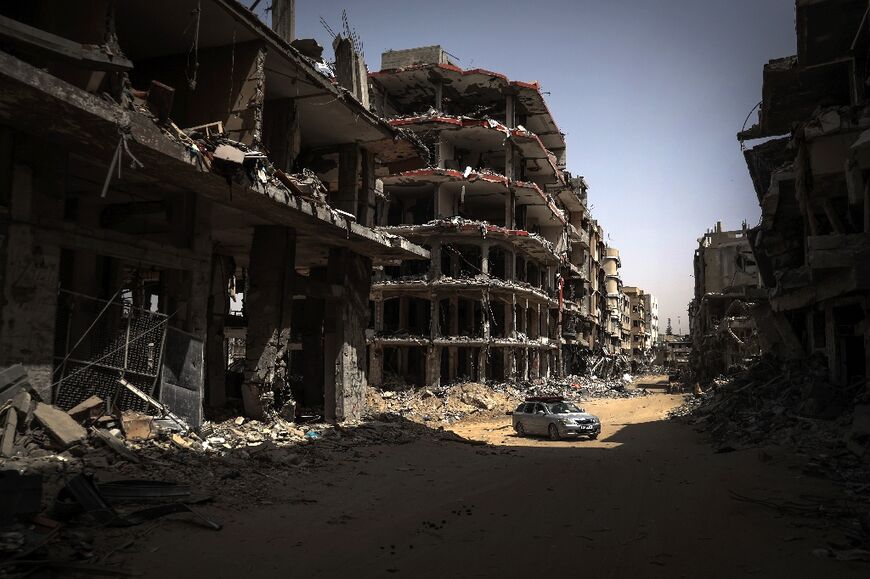 A car drives on a road lined with devastated buidings in Khan Yunis in the southern Gaza Strip destroyed in the Israel-Hamas war