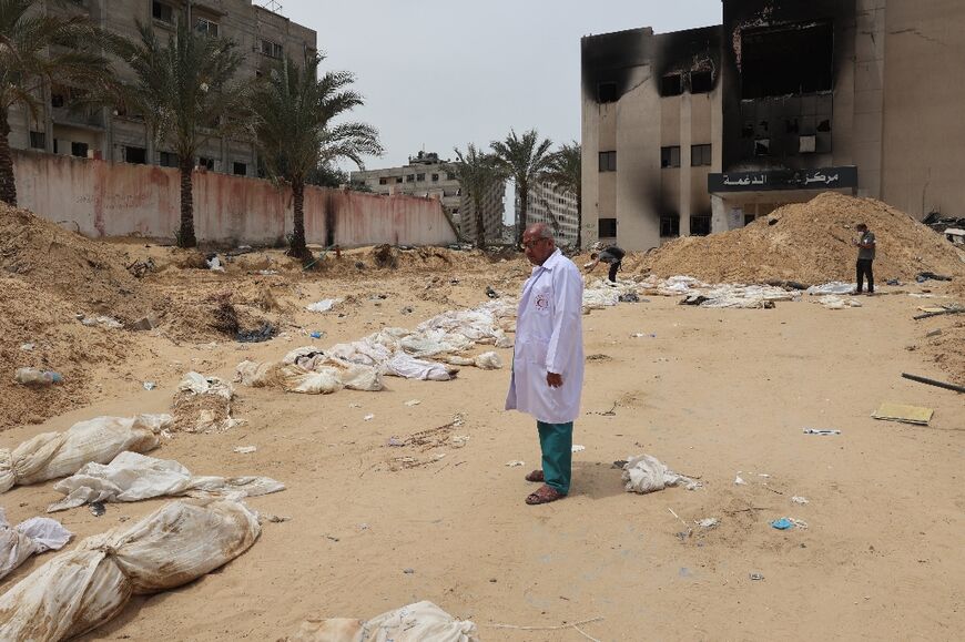 A doctor stands near bodies lined up for identification after they were unearthed at Gaza's Nasser Medical Complex