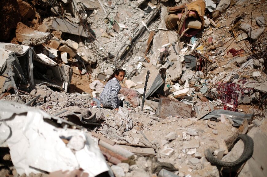 A schoolgirl sits among the ruins of Gaza City