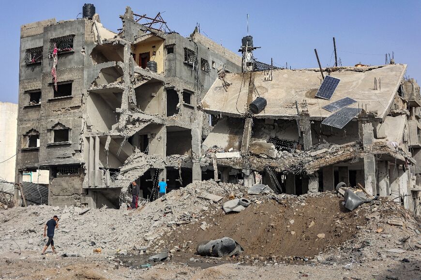 People inspect the wreckage of a partially collapsed building in Gaza City 