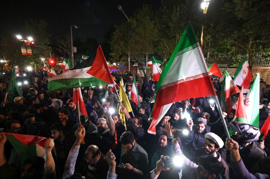 Demonstrators wave Iran's flag and Palestinian flags as they gather in front of the British Embassy in Tehran