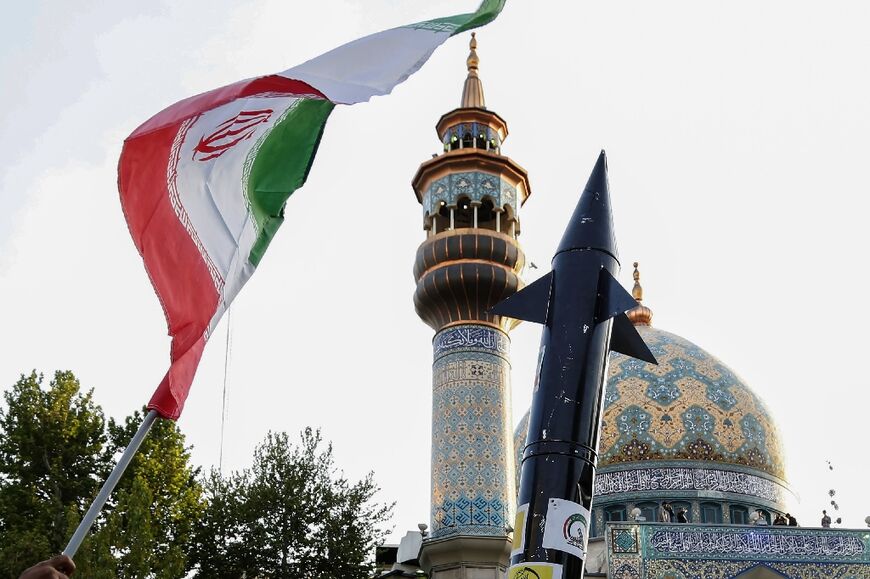 Iranians lift up a flag and the mock up of a missile during a celebration following Iran's missiles and drones attack on Israel, on April 15 2024, at Palestine square in central Tehran