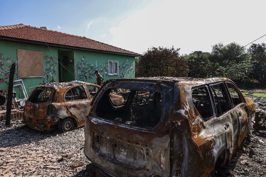 An Israeli soldier walks past charred cars in the small farming community of Netiv Haasara where Maoz Inon's parents were killed by Palestinian militants on October 7