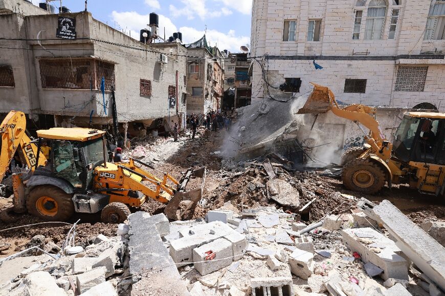 Workers clear debris in the Nur Shams camp