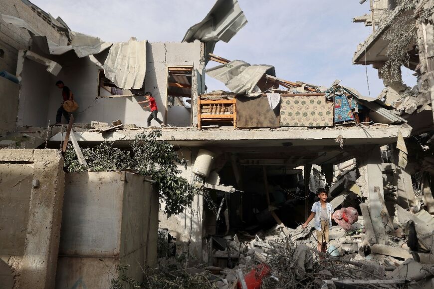 Palestinian youths search the rubble of a building hit in Israeli bombardment in Rafah, where Israel vows to send in ground troops