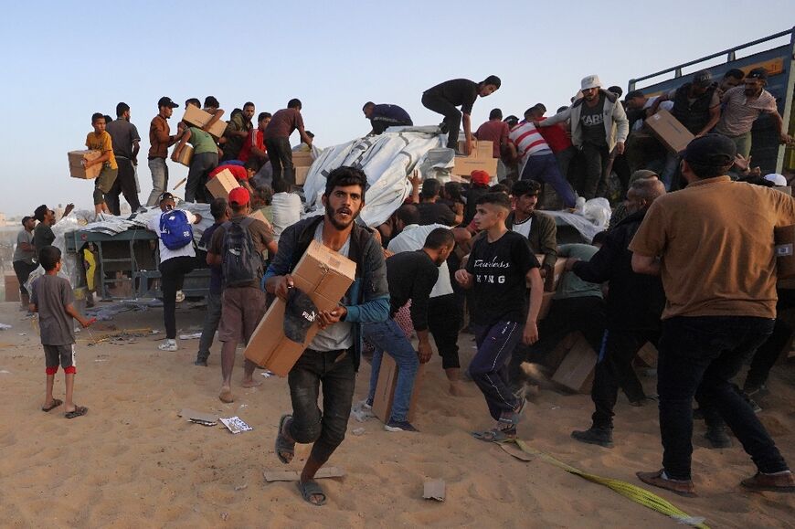 Palestinians carry boxes of humanitarian aid after rushing trucks from the US-built Trident Pier near Nuseirat in the central Gaza Strip on May 18, 2024