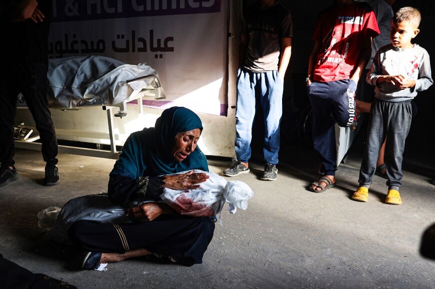 A Palestinian woman holds the shrouded body of a child  killed in Israeli bombardment, at a clinic in Rafah in the southern Gaza Strip on May 26, 2024