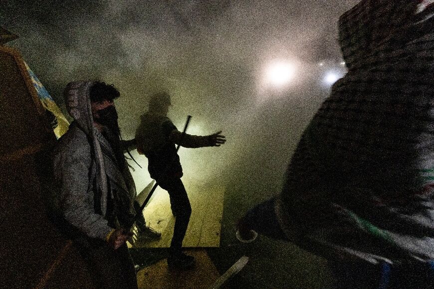 Pro-Palestinian protestors engulfed in tear gas regroup and rebuild a barricade surrounding the encampment set up on the UCLA campus in Los Angeles 