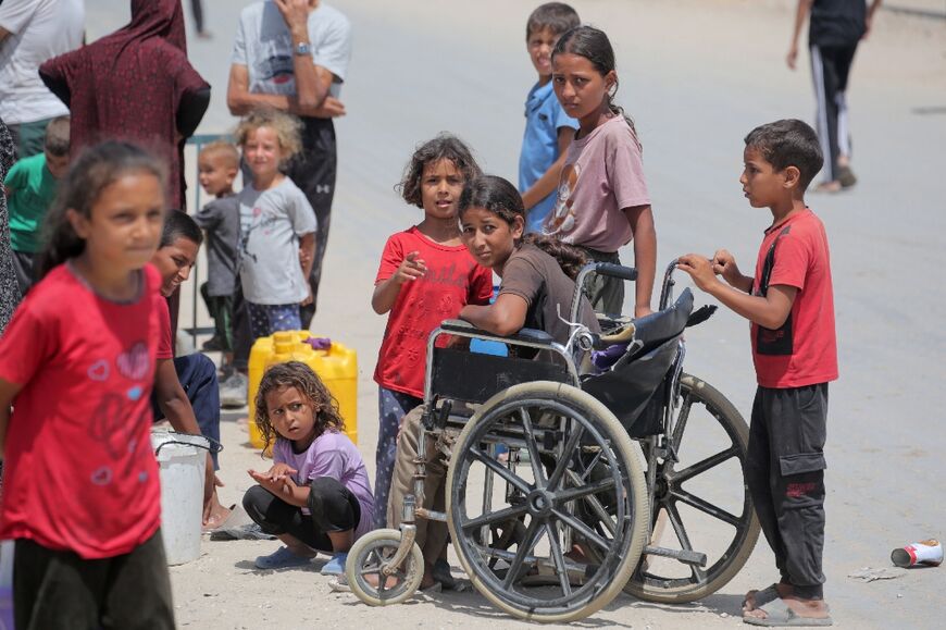 Displaced Palestinians queue for water at a camp west of Deir al-Balah in the Gaza Strip on May 21, 2024