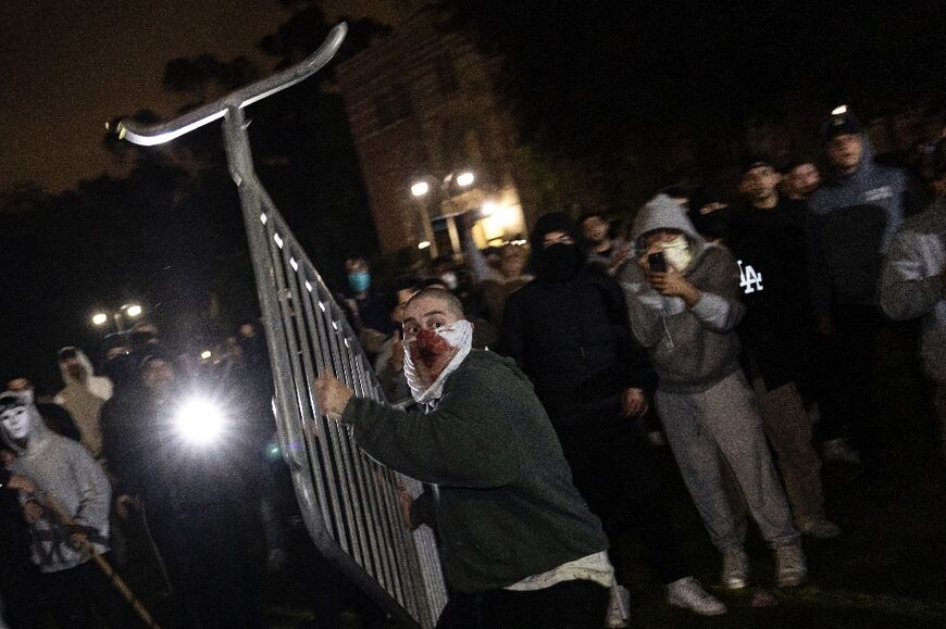 A counter protester throws a barrier at a pro-Palestinian demonstrator during clashes at the UCLA campus in Los Angeles 