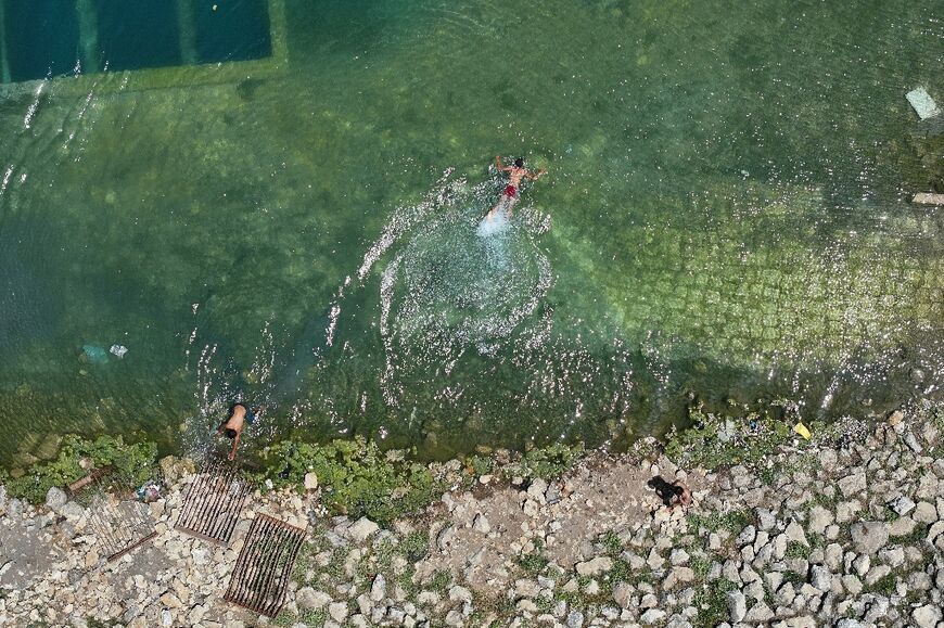 Children swim in an canal carrying water from the Balaa dam