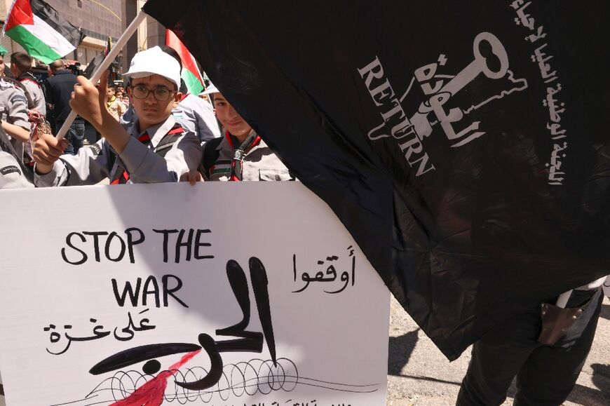 Palestinian youths hold up banners and flags during a rally in the southern West Bank city of Hebron