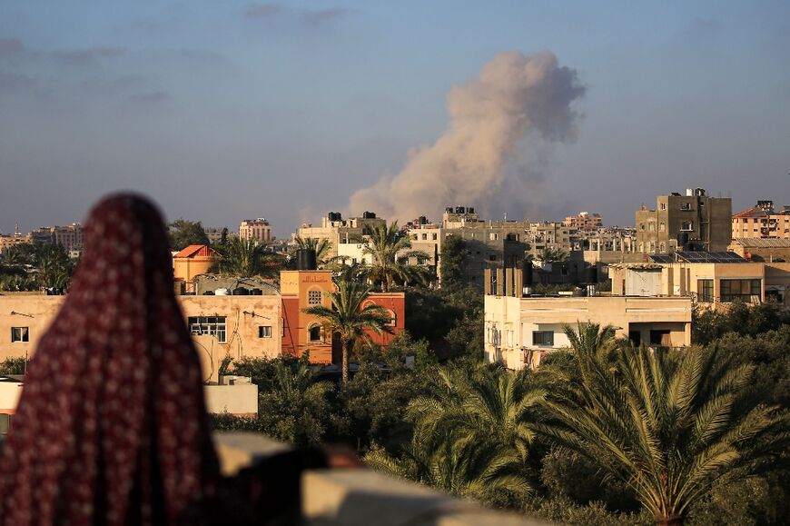 A Palestinian woman watches as smoke billows following an Israeli strike south of Gaza City