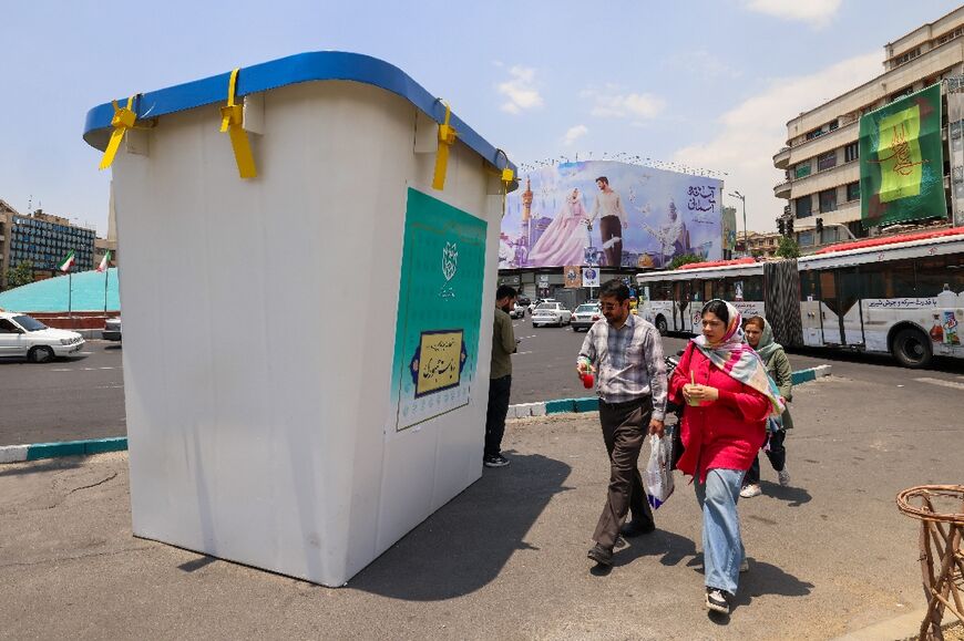 People walk past a replica of a ballot box installed on a street in Tehran 