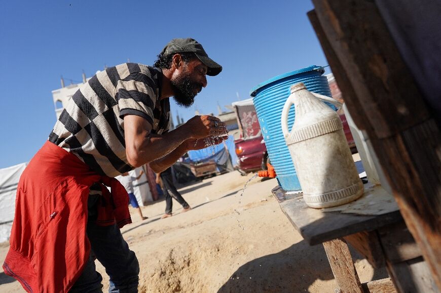 A displaced Palestinian man splashes his face with water during a heatwave in Deir al-Balah, in the central Gaza Strip