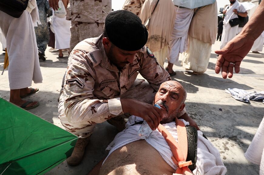 A member of the Saudi security forces helps a pilgrim affected by scorching heat as Muslim pilgrims arrive to perform the symbolic 'stoning of the devil' ritual in Mina