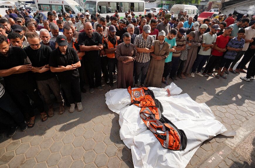 Colleagues and other mourners pray over the bodies of four civil defence volunteers killed during Israeli bombardment at Nuseirat refugee camp, central Gaza